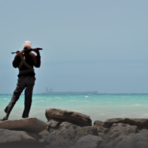 Somalian pirate looks out over the Gulf of Aden toward a shipping vessel.