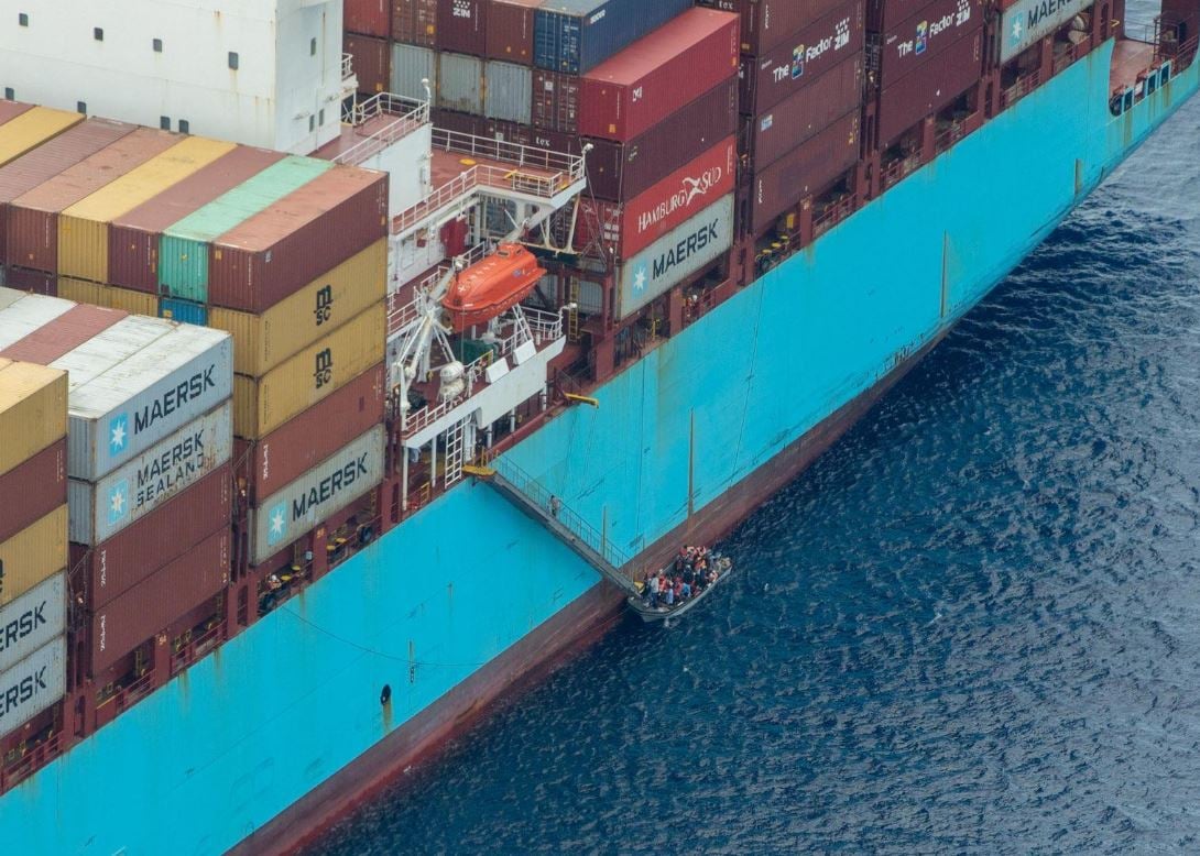 Ambrey Insight image showing a container ship with a small boat carrying people alongside the vessel during a maritime assistance operation